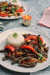 lomo saltado, peruvian, stir-fry, beef, french fries, rice, cilantro, tomatoes, candle, recipe, easy, tasty, napkin, fork, knife, plate